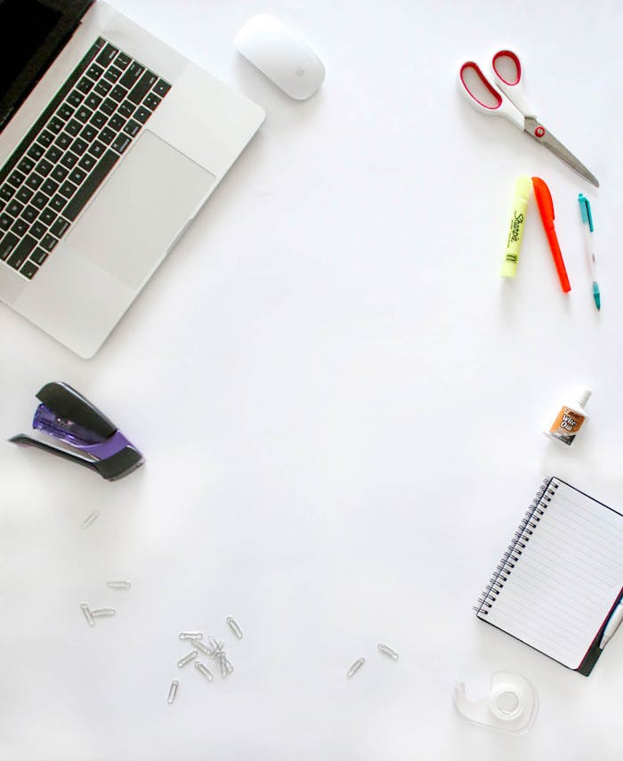 Organized office supplies on a desk including laptop, scissors, and notebook.