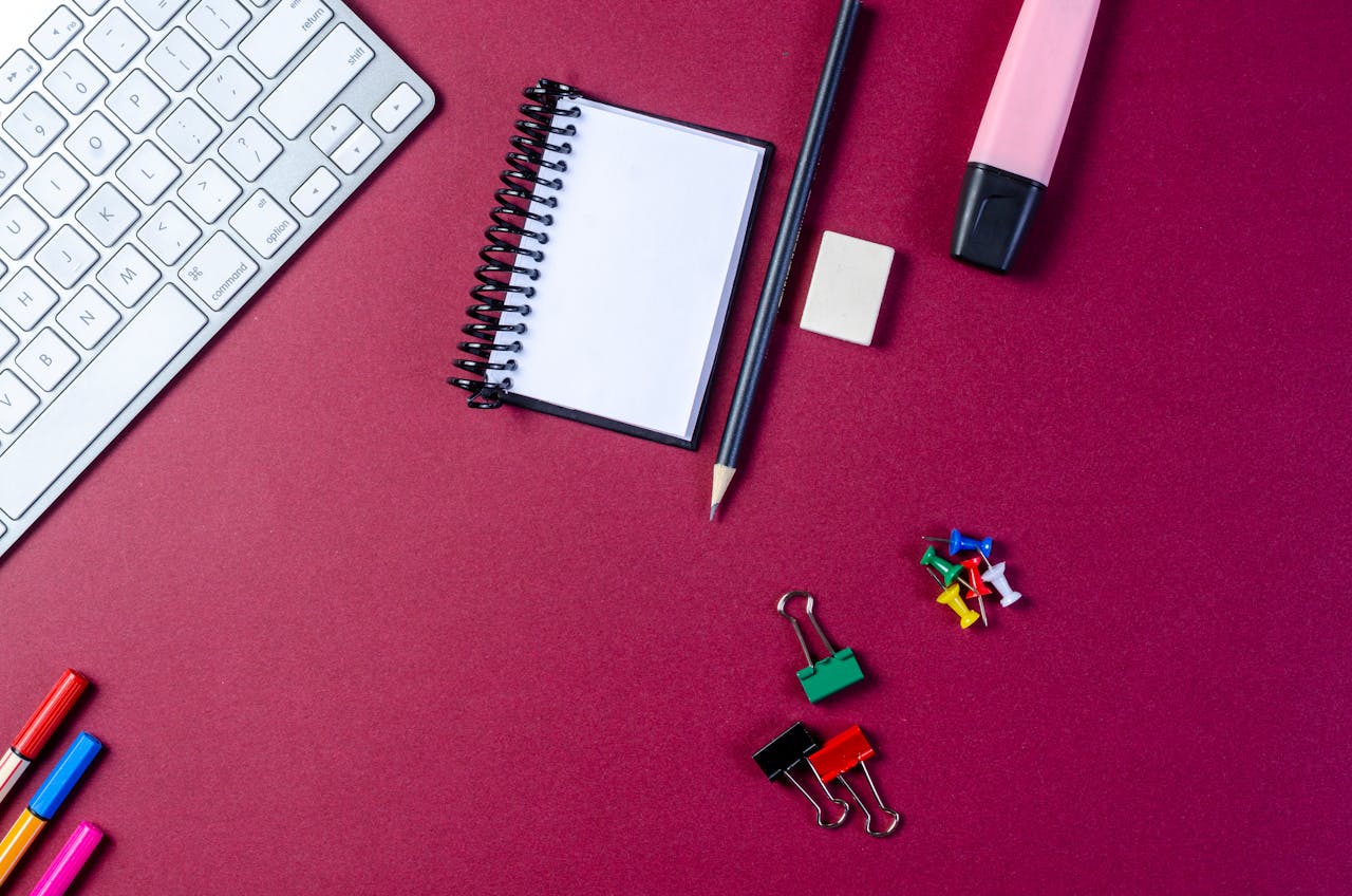 Flat lay of stationery items and keyboard on a vibrant desk.