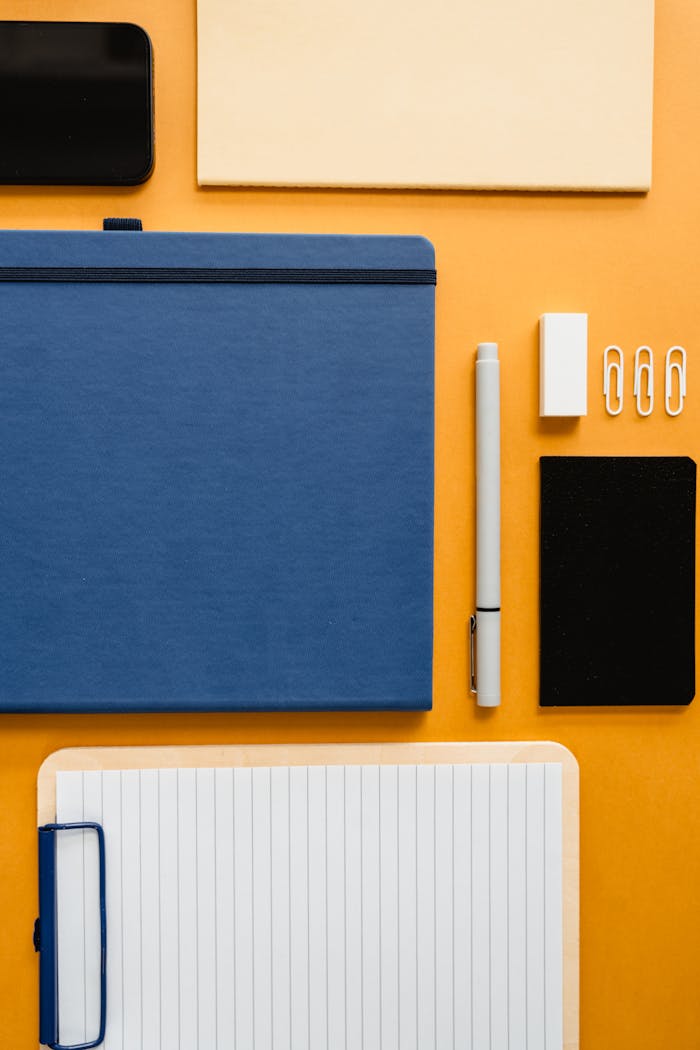 Top-down view of various office supplies on a vibrant yellow background, showcasing organization and style.
